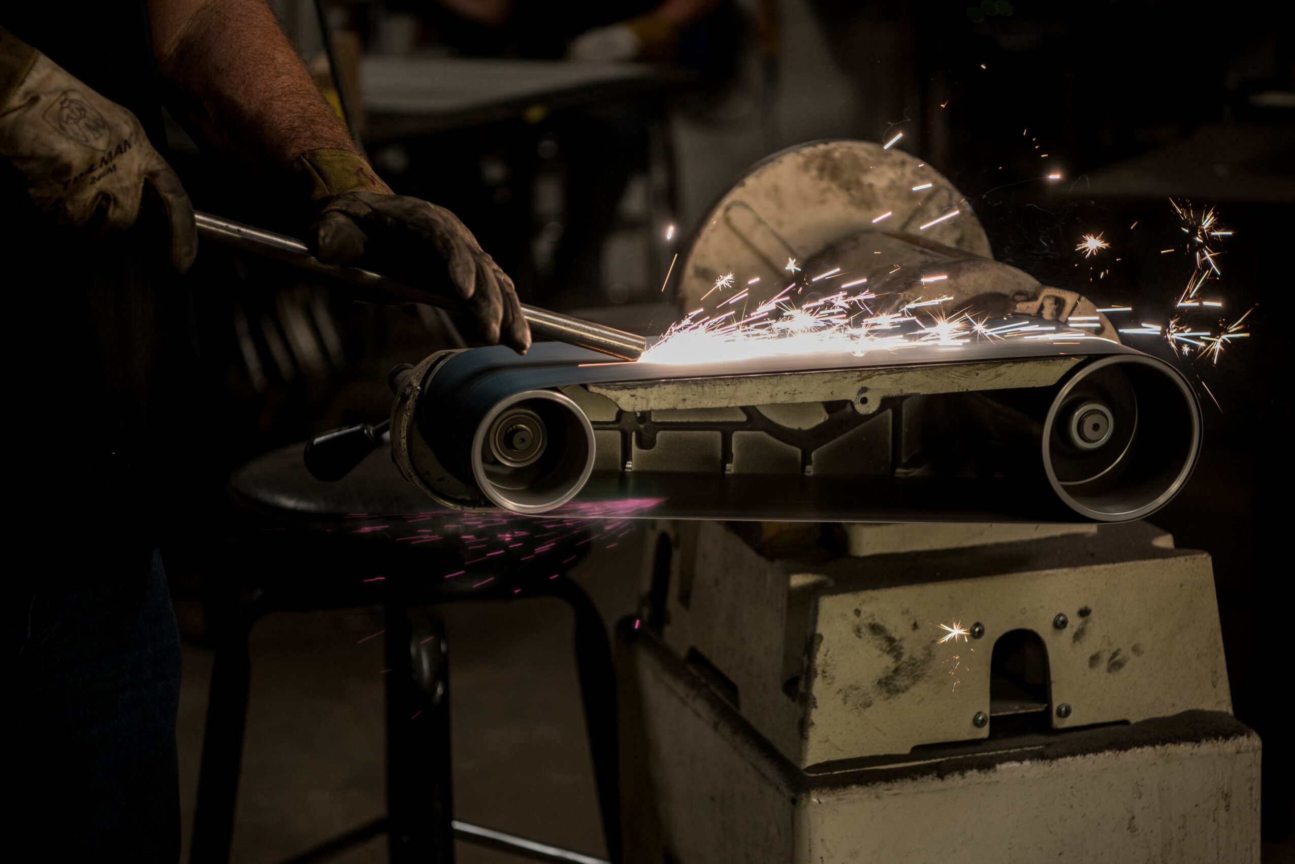 Worker cutting metal with a circular saw, sparks flying, on a workbench in a workshop.