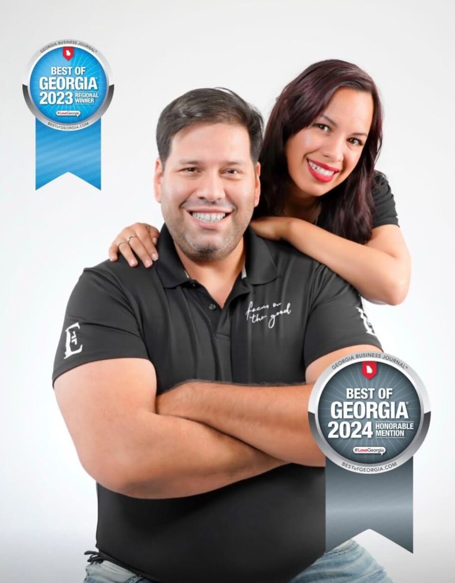 A smiling man with crossed arms and a woman with her arm around his shoulder, both looking at the camera.
