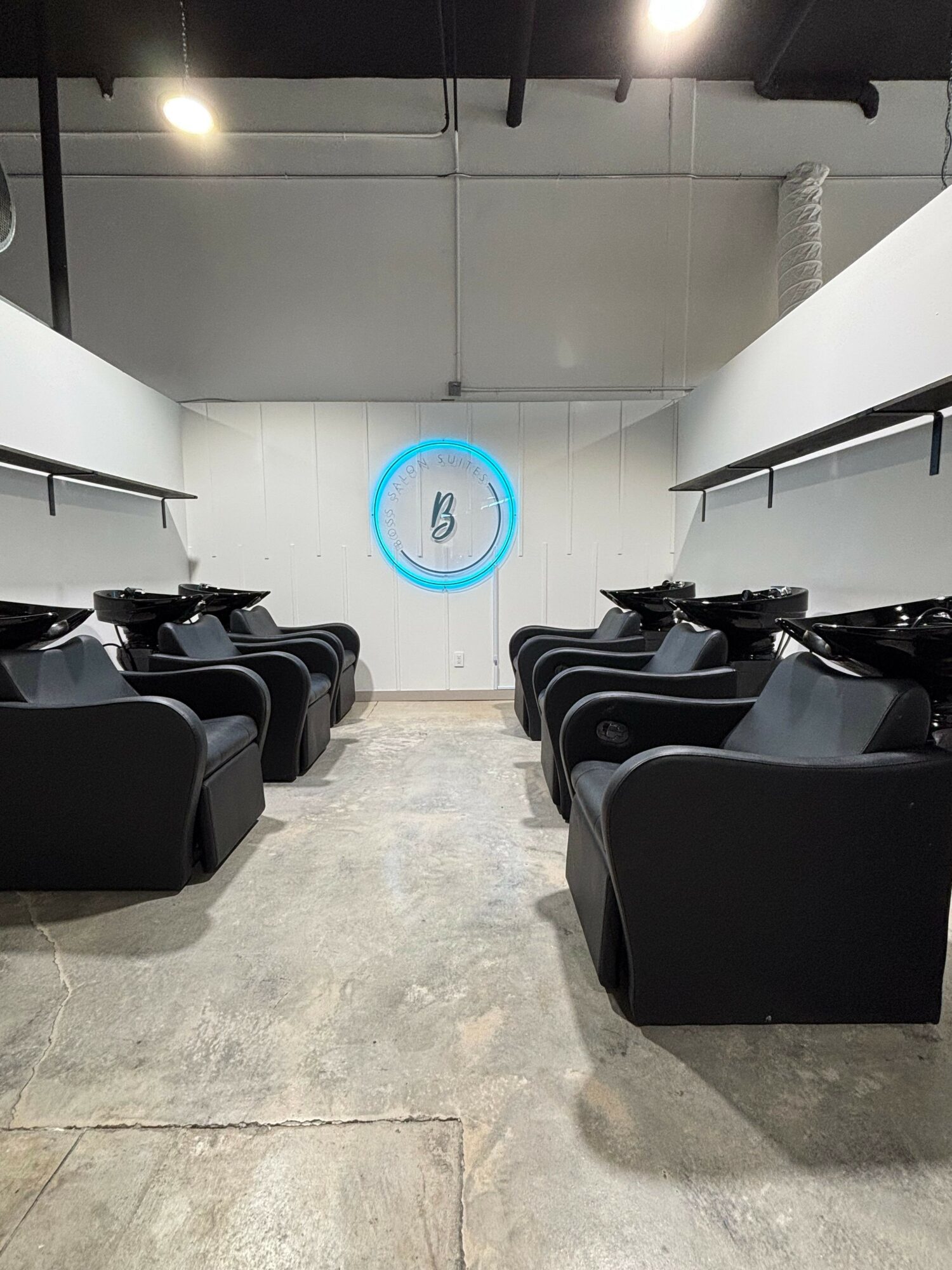 Empty black chairs in a room with white walls and a concrete floor, with a blue circle and number 3 on the wall.