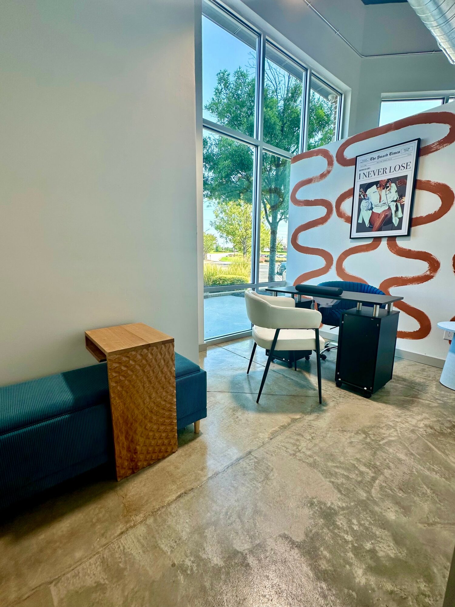 Interior space with large window, seating area, and a decorative wall with framed artwork, natural light, and a view outside.