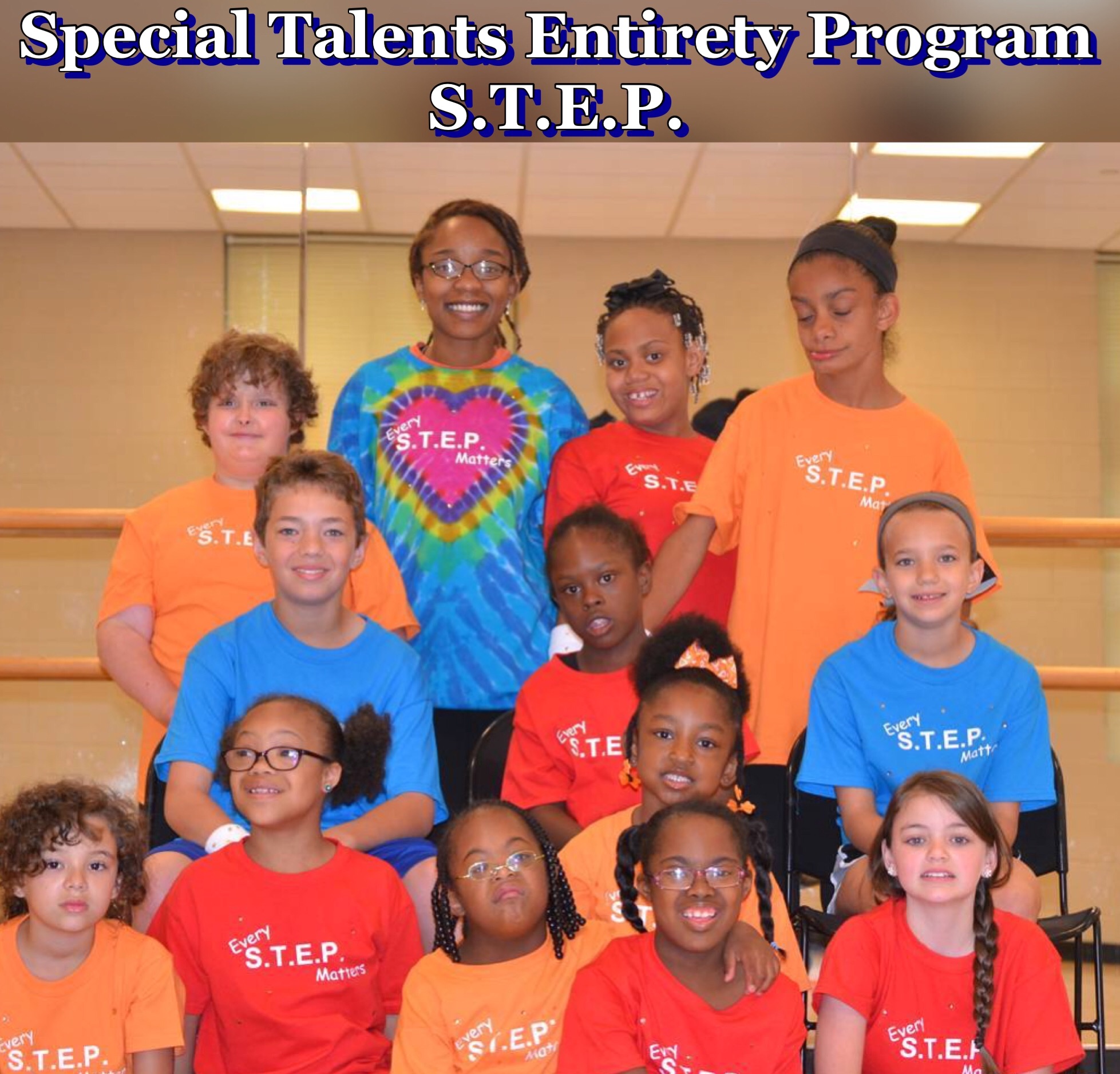 Group of children and an adult woman in colorful shirt, all wearing S.T.E.P. shirts, in a room with mirrors.