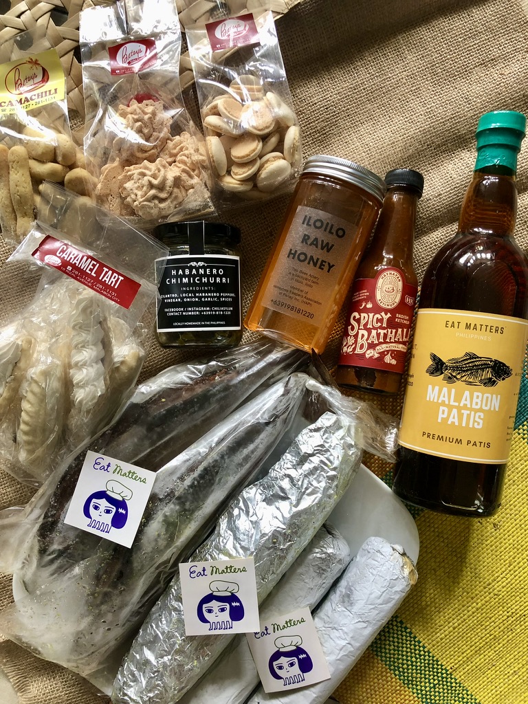 Assorted snacks, honey jar, spicy bath product, Malabon Patis bottle, and wrapped food items on a surface.