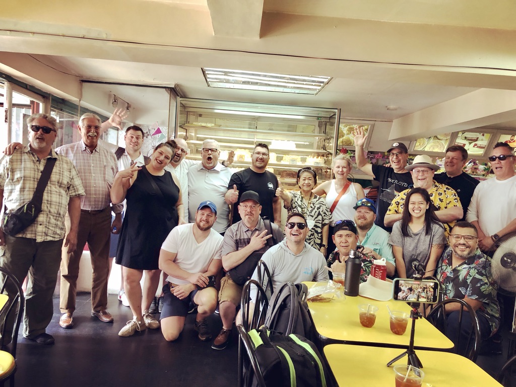 Group of people gathered around a table in a restaurant, smiling and posing for the photo.