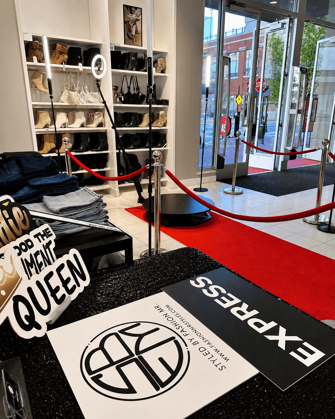 Store entrance with red carpet, shoe display shelves, and a sign reading 'Queen' and 'Express'.