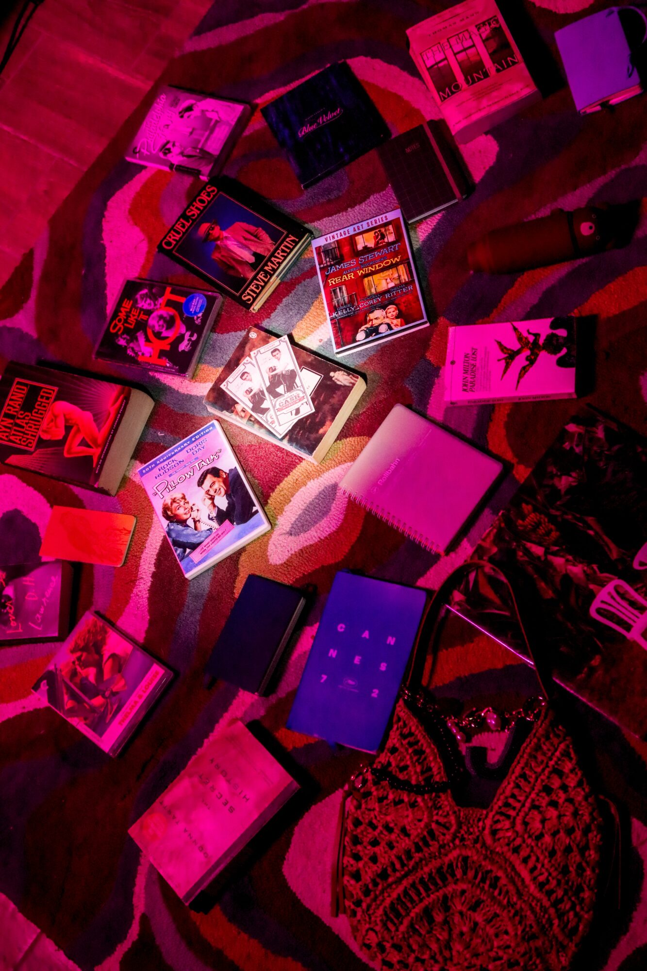 Collection of colorful books and magazines scattered on a surface with a patterned cloth nearby.