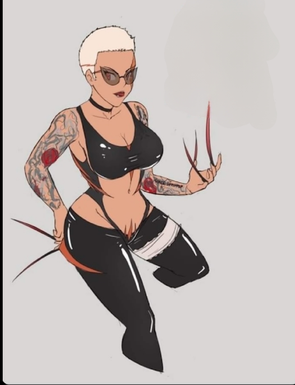 A tattooed woman with short blonde hair, sunglasses, and black clothing, sitting with one knee up and hand resting on her knee.