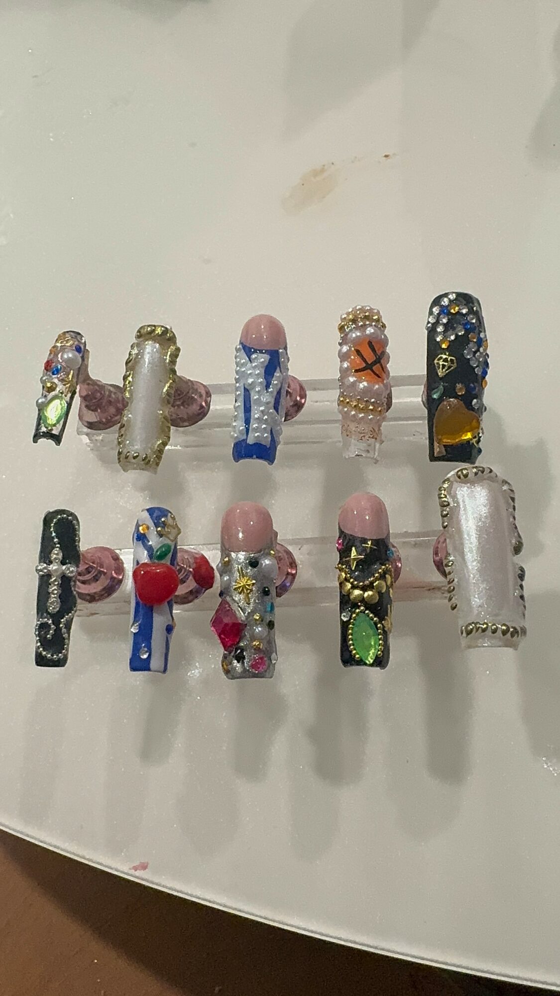 Collection of 12 decorated glass beads with various colors and patterns, arranged in two rows on a white surface.