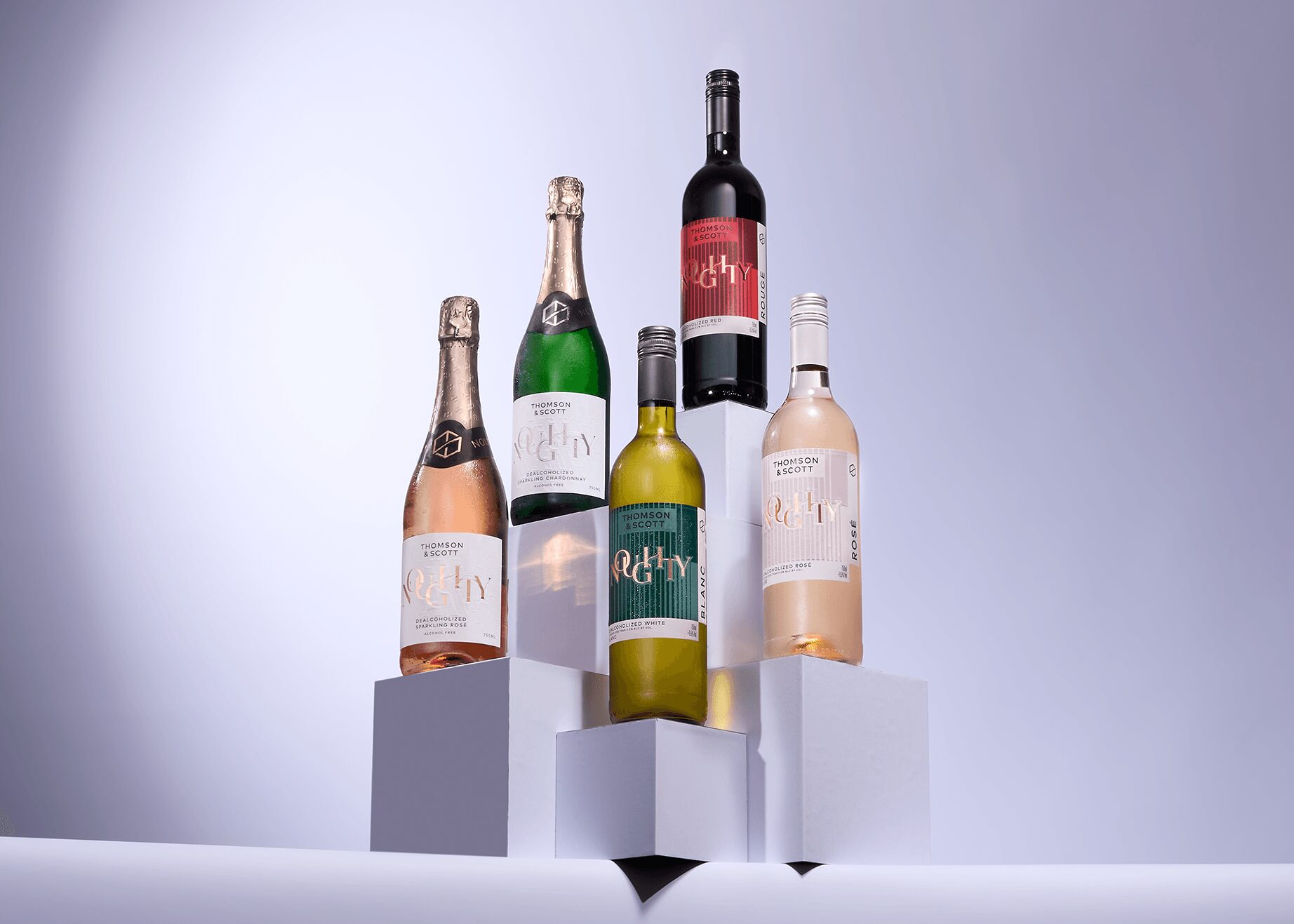 Five bottles of wine and champagne on white pedestals against a light background.