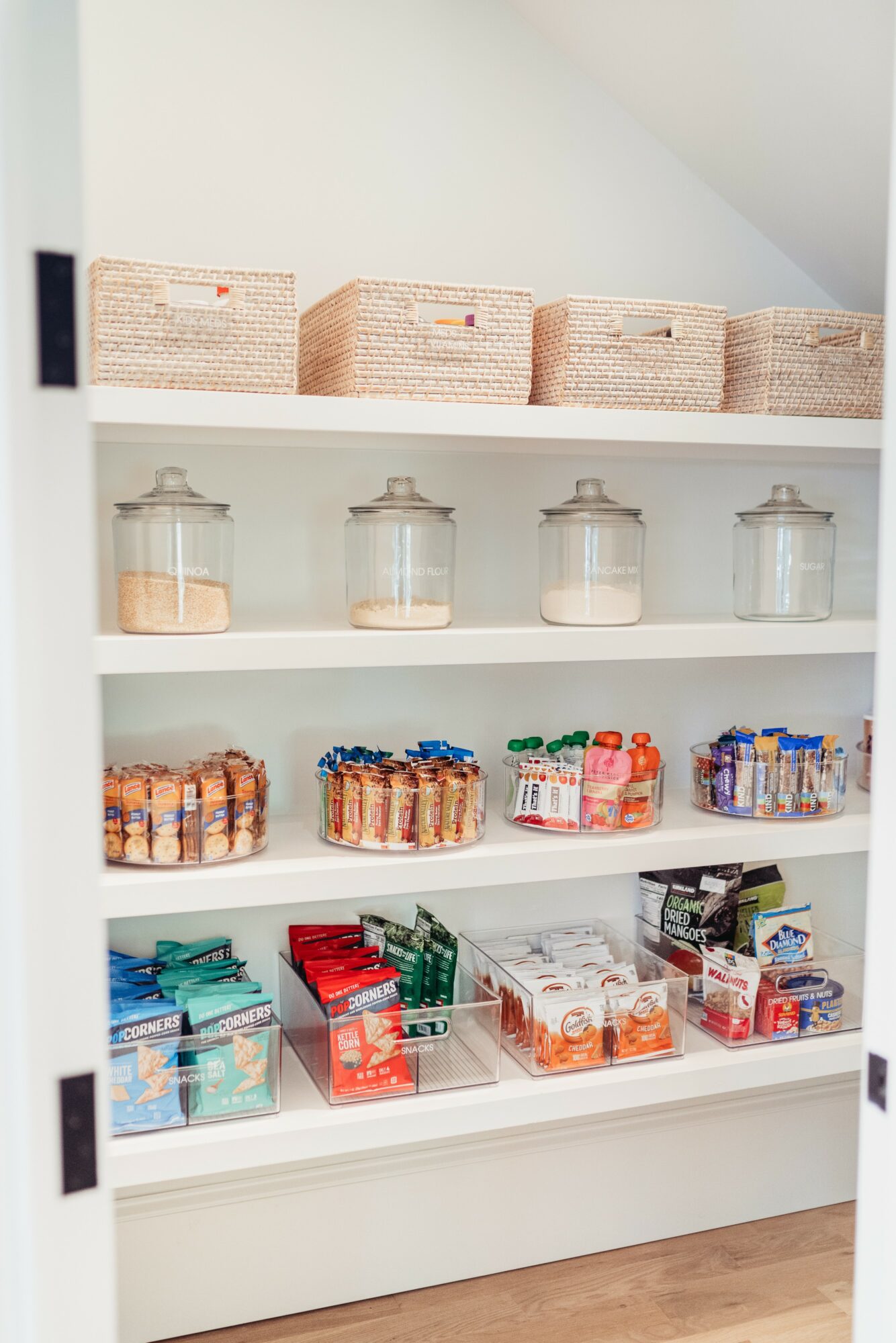 Shelves with jars, boxes, and packaged snacks in a store or pantry, viewed from the front.
