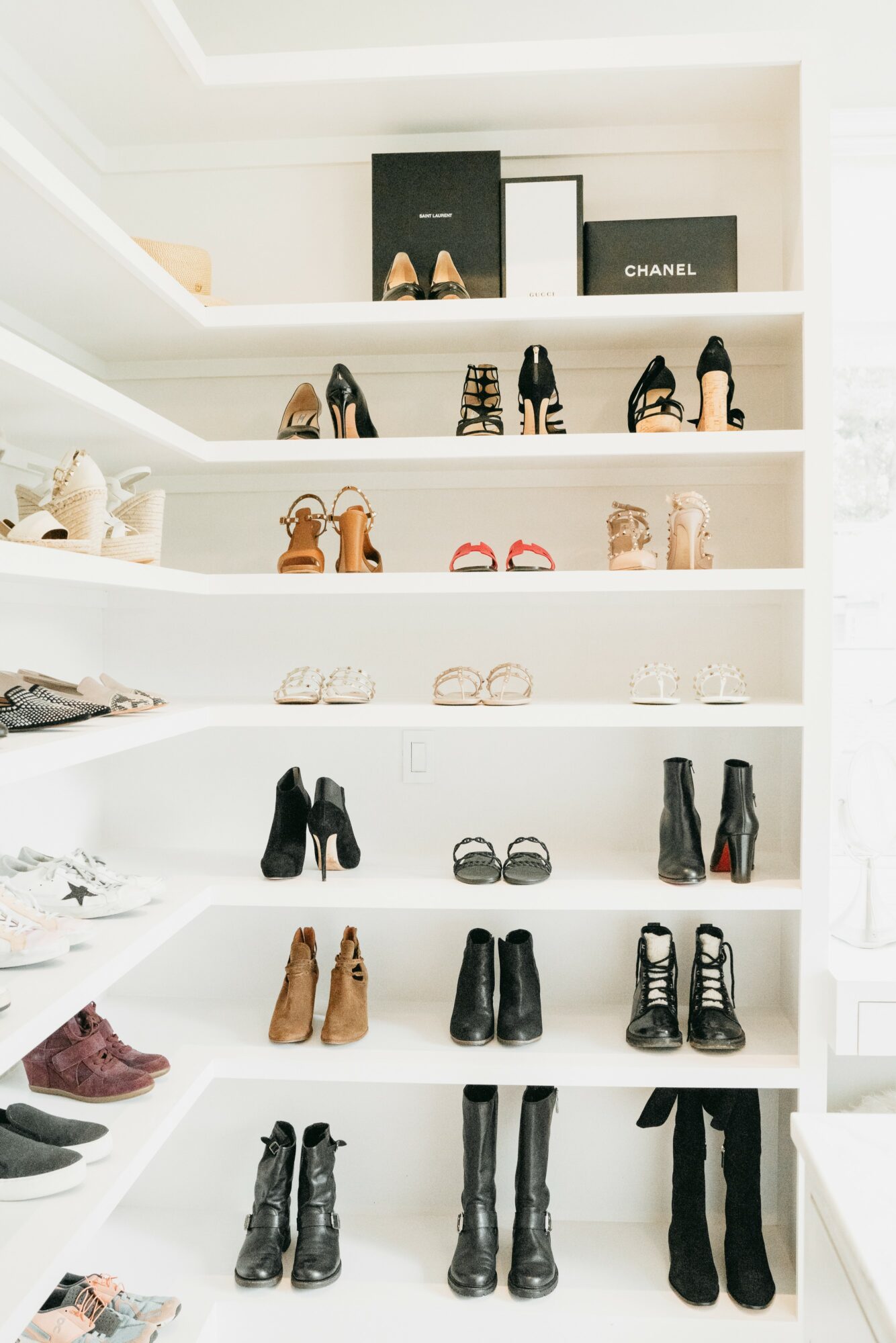White shelves with shoes, handbags, and framed pictures, arranged neatly in a closet or display area.