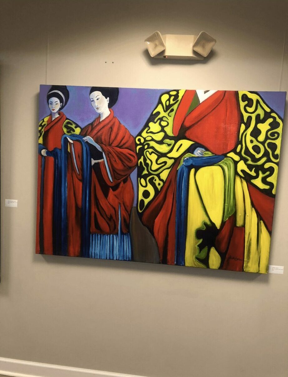 Colorful abstract painting with three figures, bold patterns, and vibrant colors on a wall, with a light fixture above, 20 words.