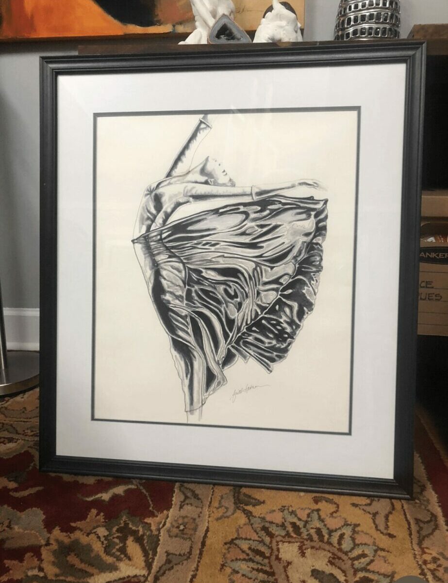 Framed black and white abstract artwork with intricate lines, leaning against a wall on a patterned rug.