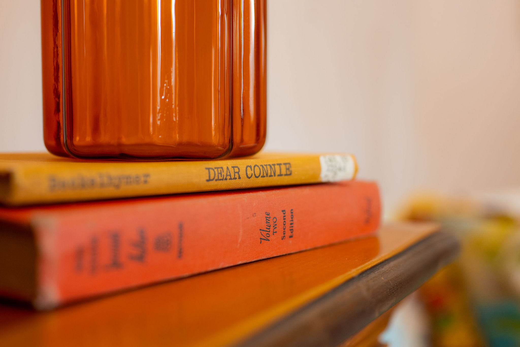 Stack of books on a wooden surface with a blurred background, focusing on the spines of the books.