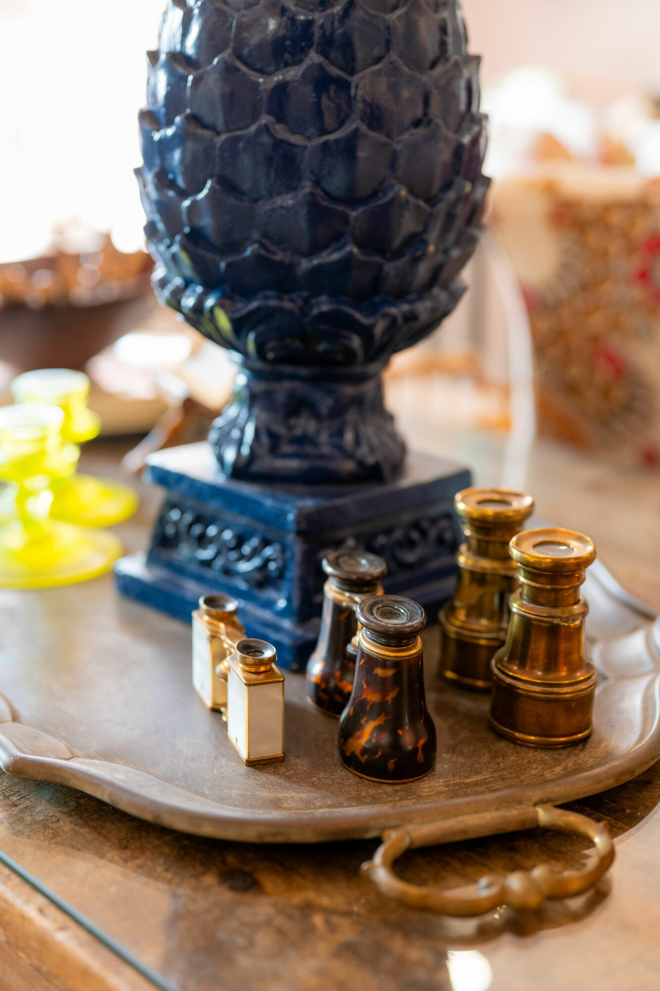 Decorative black vase with a textured surface on a wooden tray, surrounded by small gold and black chess pieces, with blurred background.