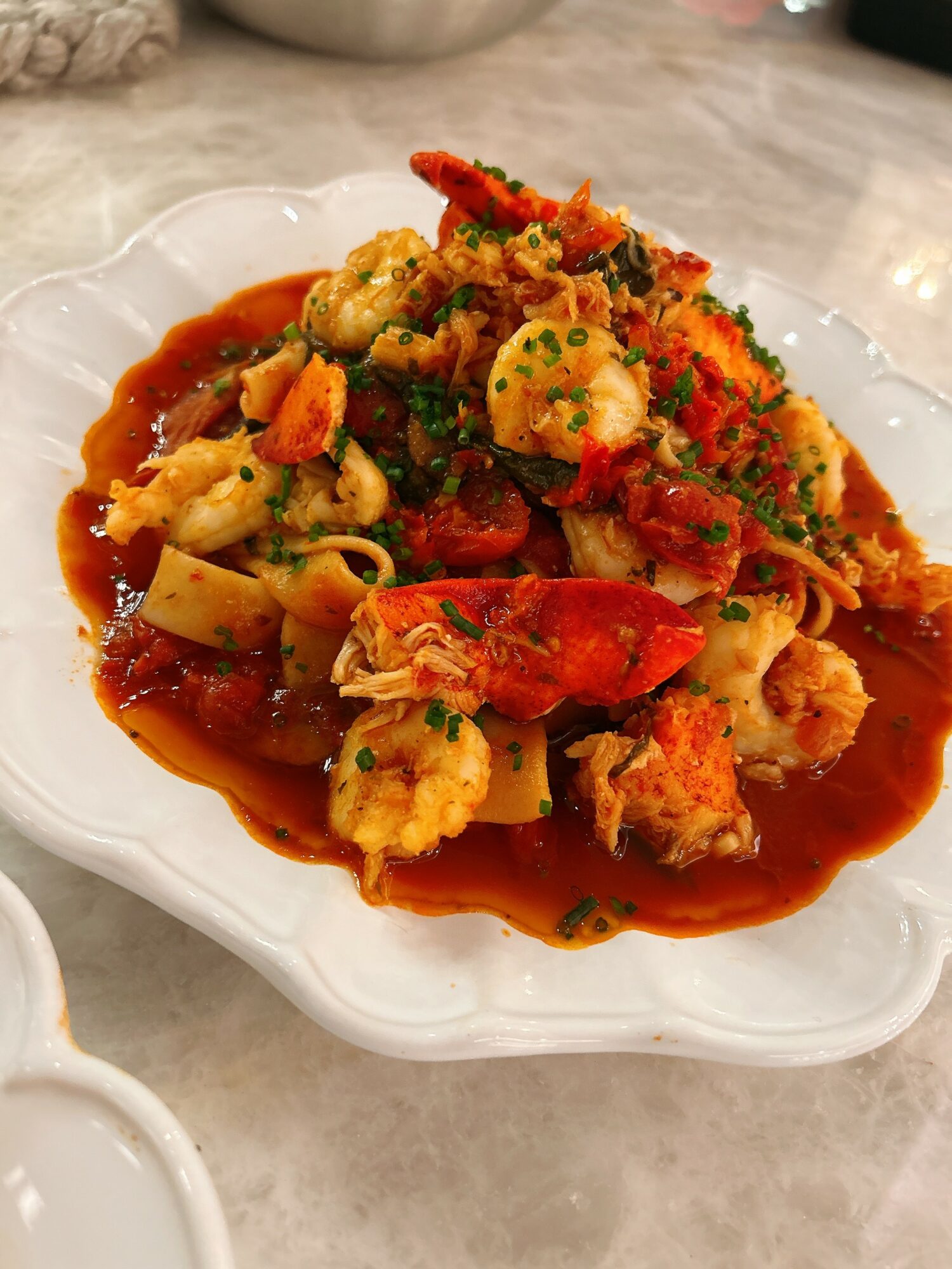 Dish with vegetables and sauce on a white plate, garnished with herbs, on a marble surface.