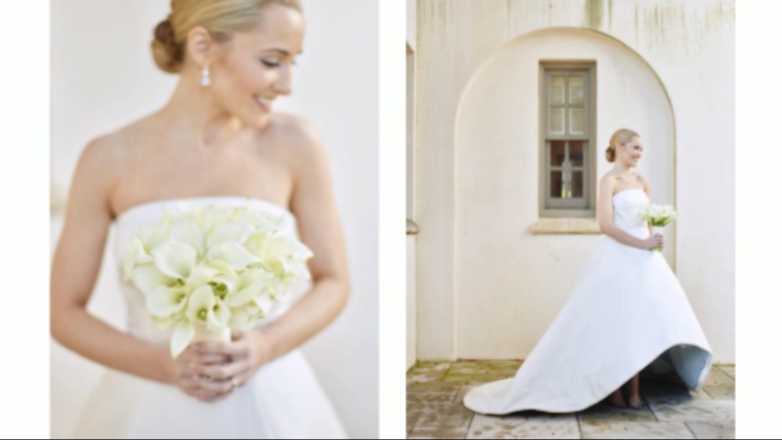 Bride holding a bouquet of white flowers, smiling, wearing a strapless dress, with her hair in an updo.