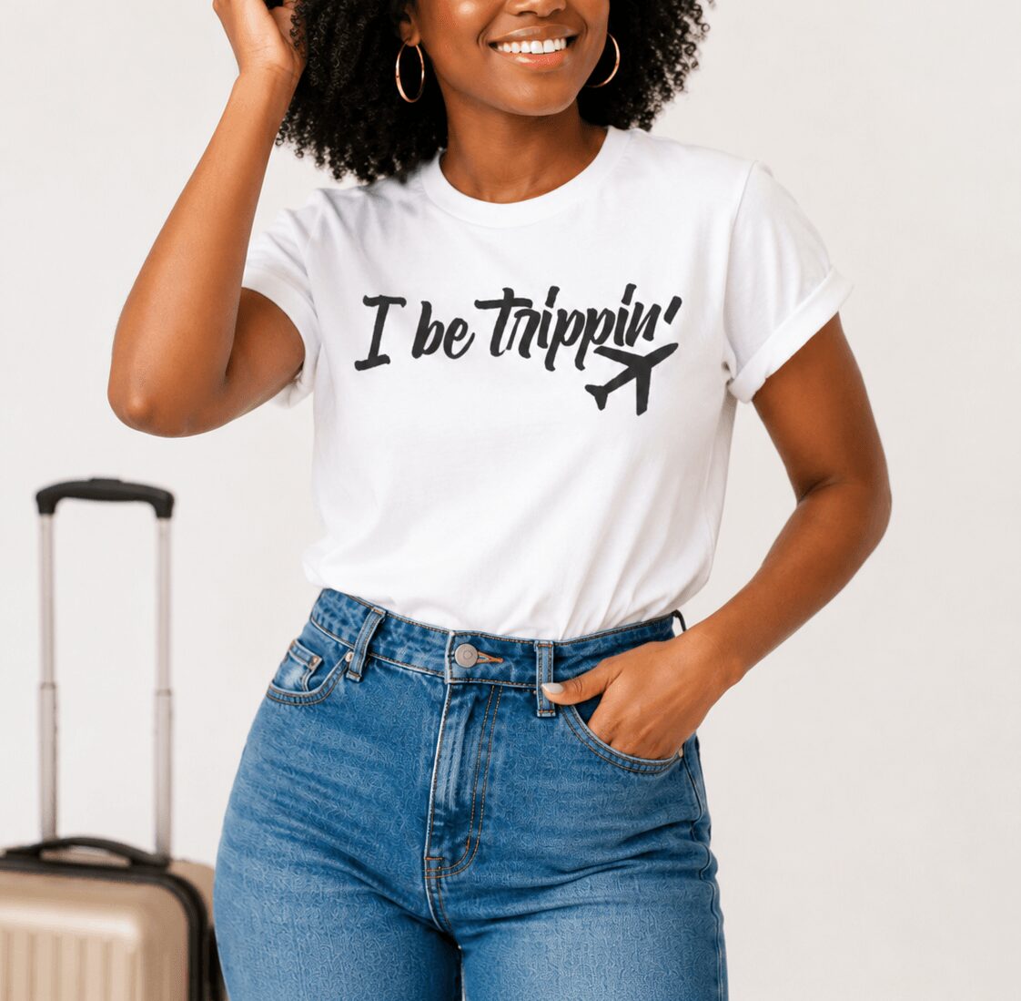 Woman smiling, wearing a white T-shirt with text and an airplane graphic, and blue jeans, standing with hand on hip.