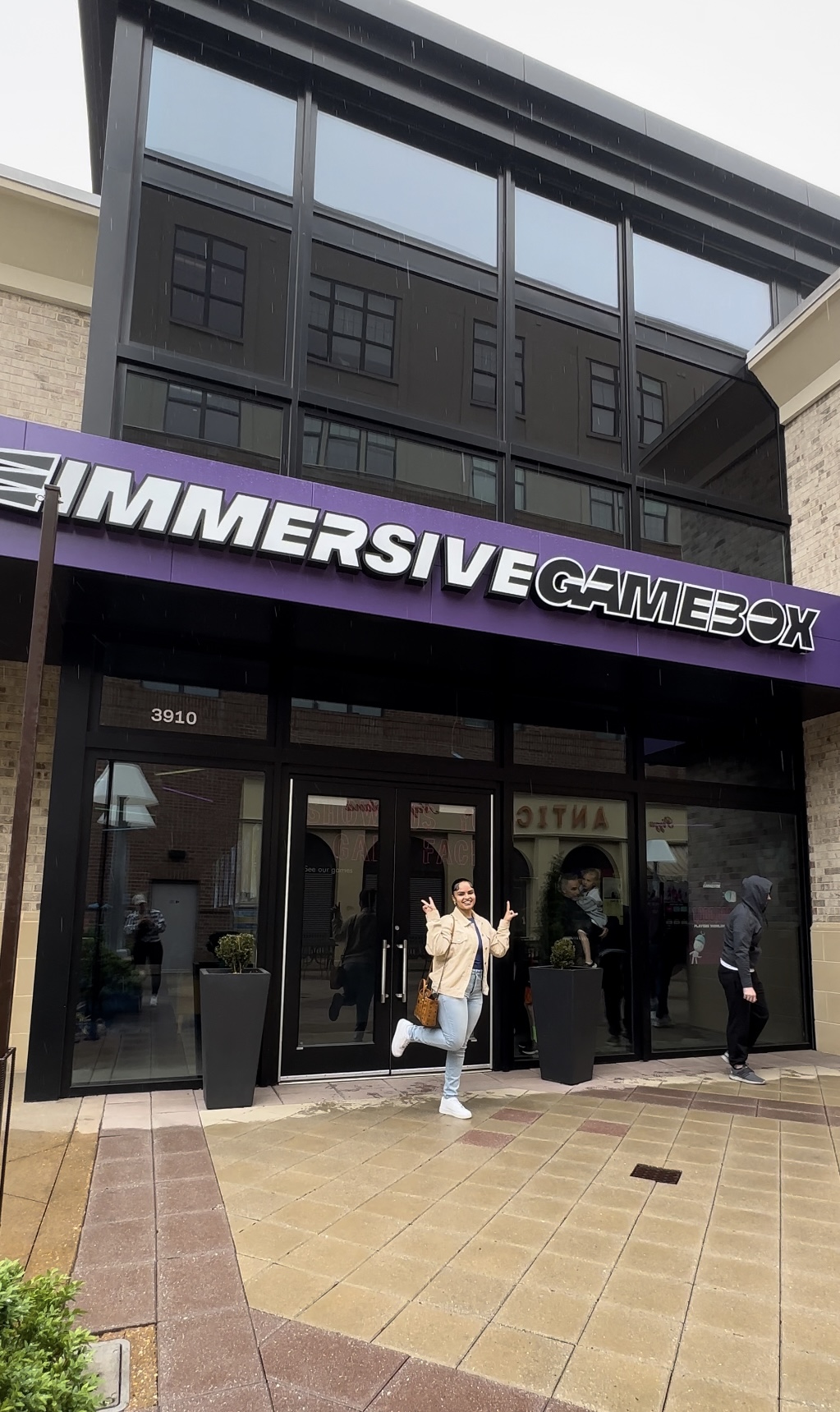Building with large glass windows and a sign reading 'SUMMERSIVE GAMEBOX' above the entrance, people walking outside.