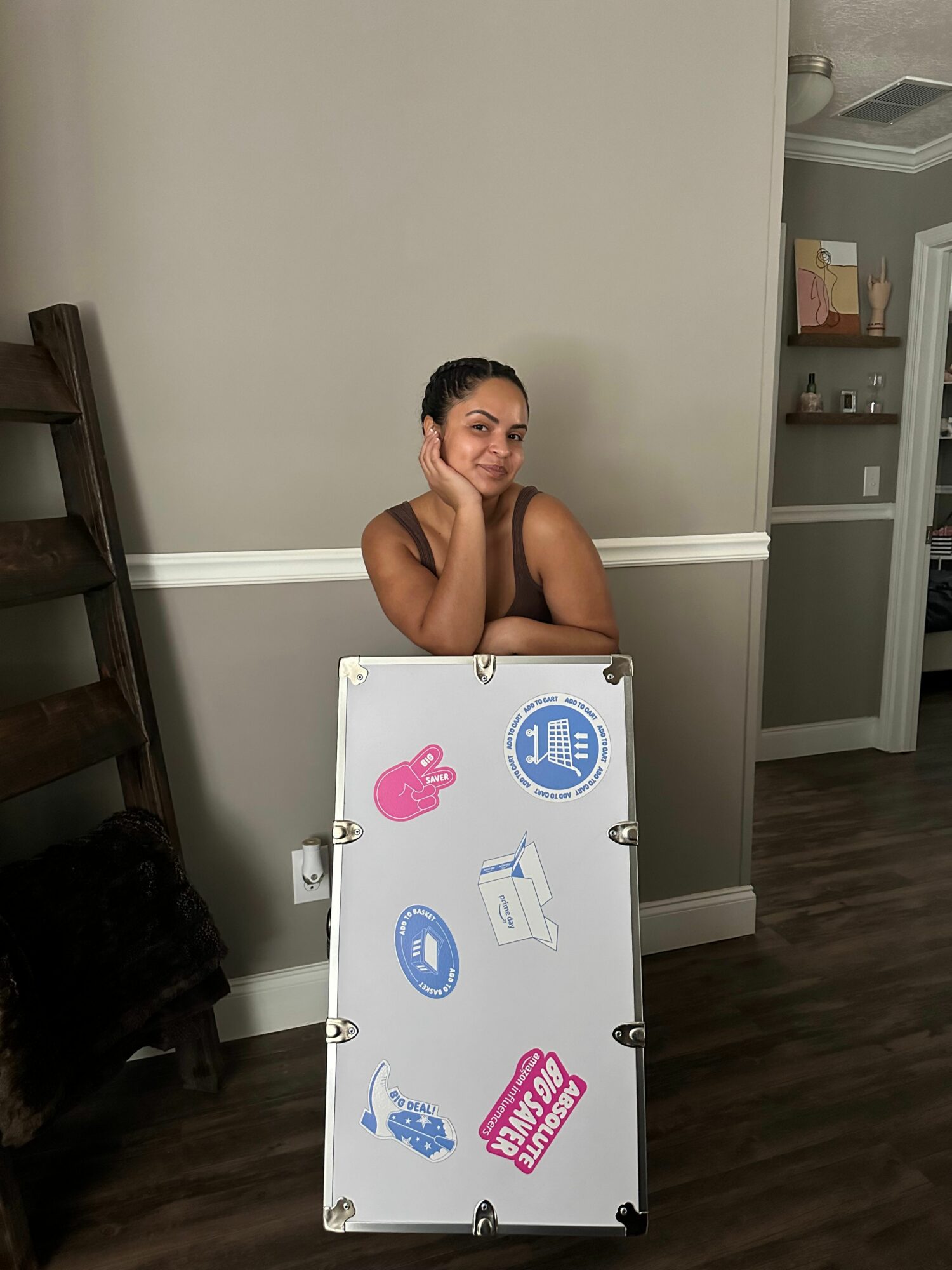 Woman leaning on a whiteboard with stickers, in a room with gray walls and wooden floor.