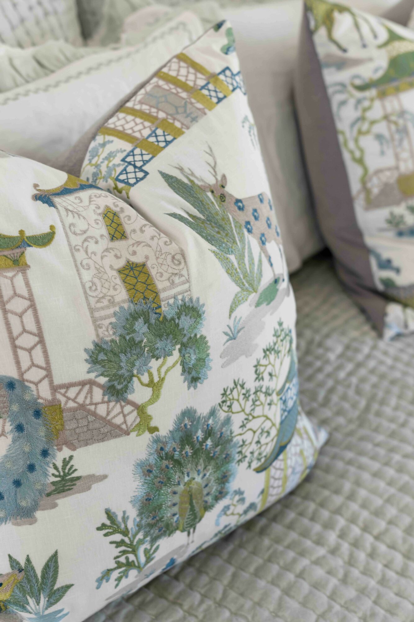 Decorative pillows with botanical and geometric patterns on a textured surface.
