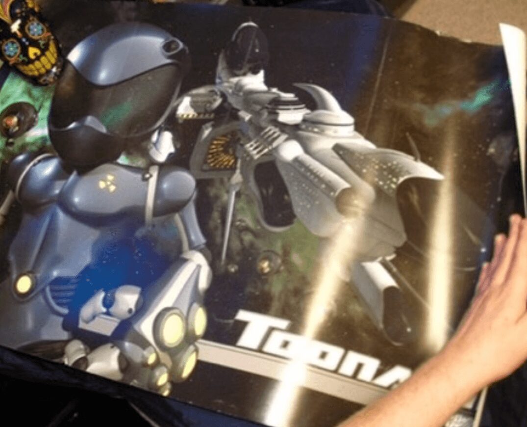 Robot and spaceship models displayed on a surface with a space-themed background, partially covered by a person's hand.