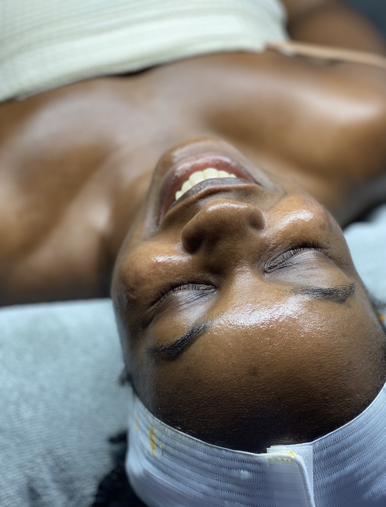 Person lying down with eyes closed, smiling, wearing a headband, in a medical setting.