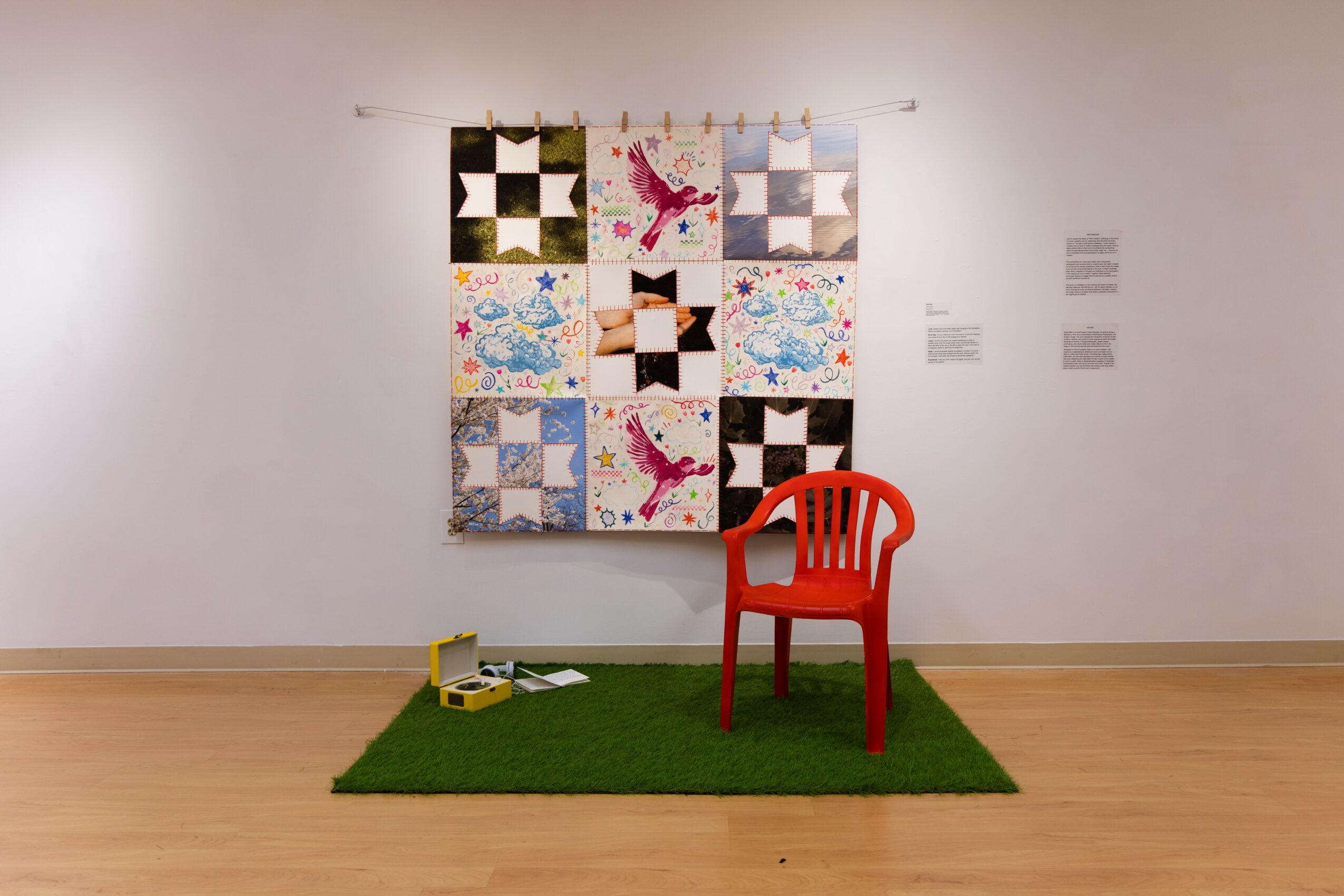 Colorful quilt with various patterns hangs on a white wall, a red chair on green carpet, and art supplies on the floor.