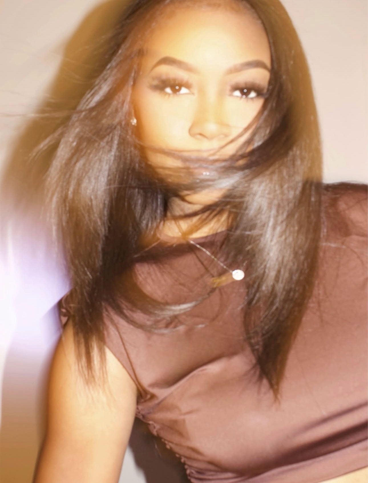 Young woman with long hair, wearing a brown top, looking at the camera with a slight smile.