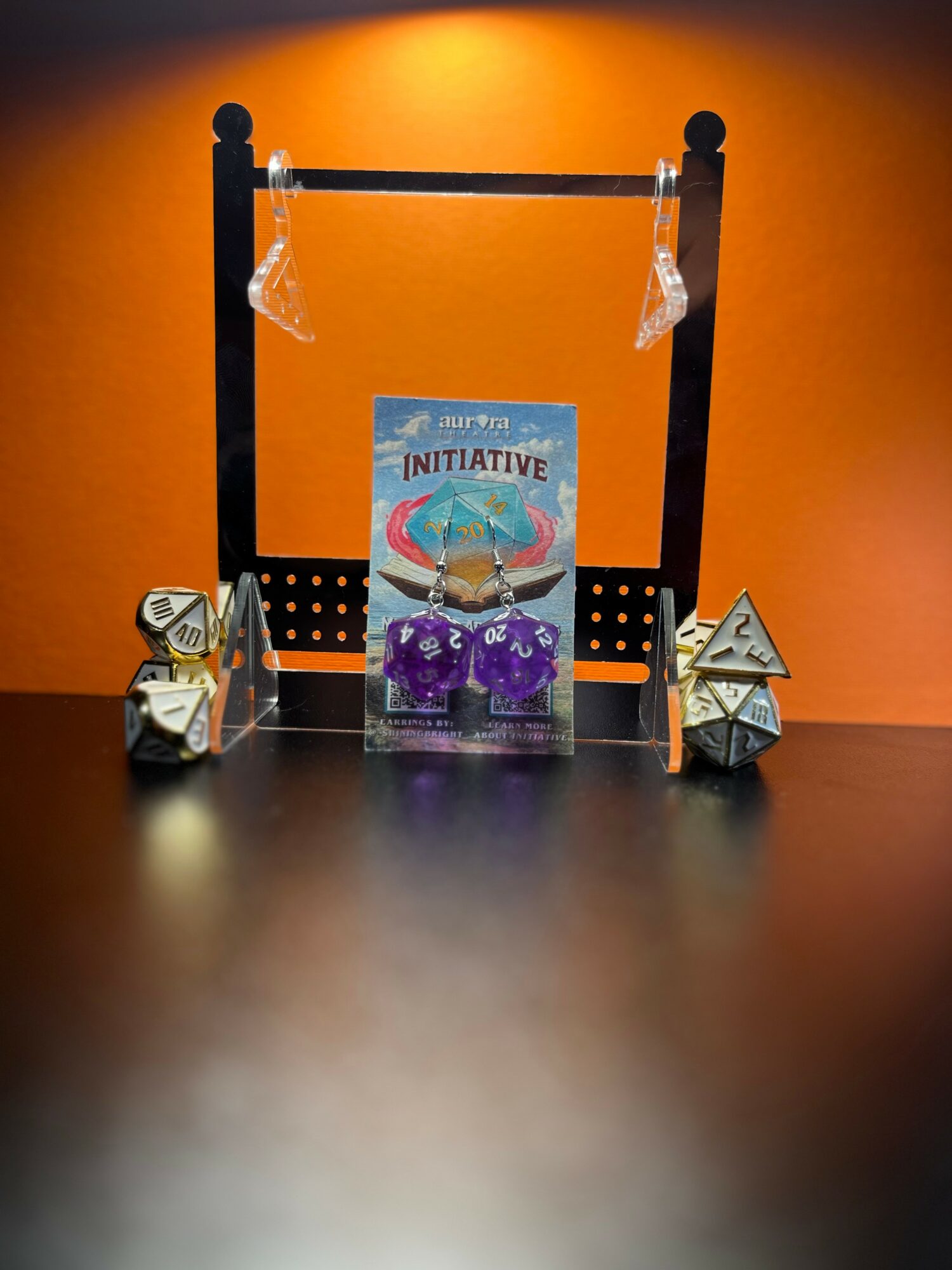 Display with a sign, two dice, and two small pyramid-shaped objects on a black surface against an orange background.