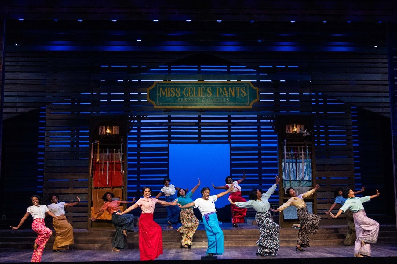 Group of people on stage performing in front of a sign that reads 'Miss Giles Pants'.