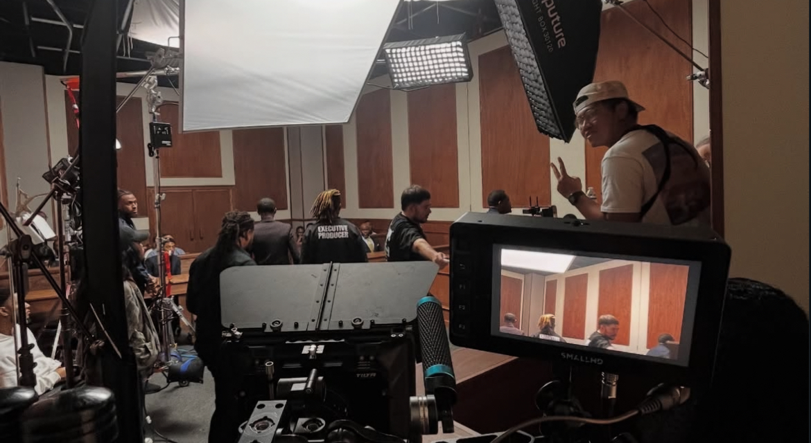 People in a studio with cameras and lighting equipment, some watching a screen, others working or observing.