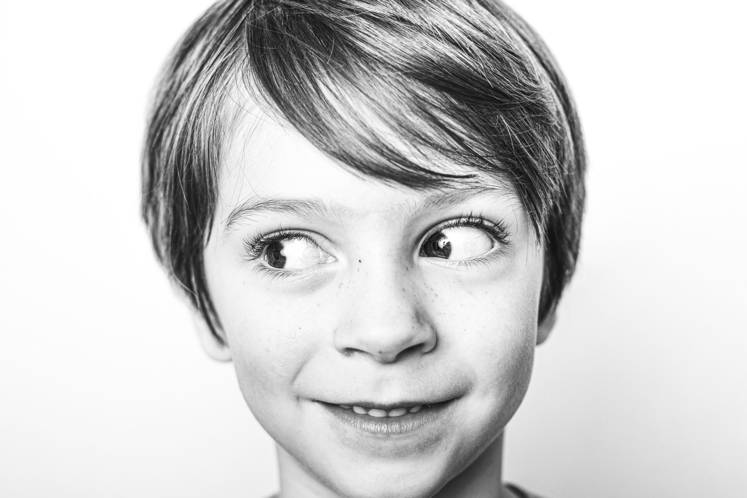 Child with short hair looking to the side, smiling slightly, in black and white.