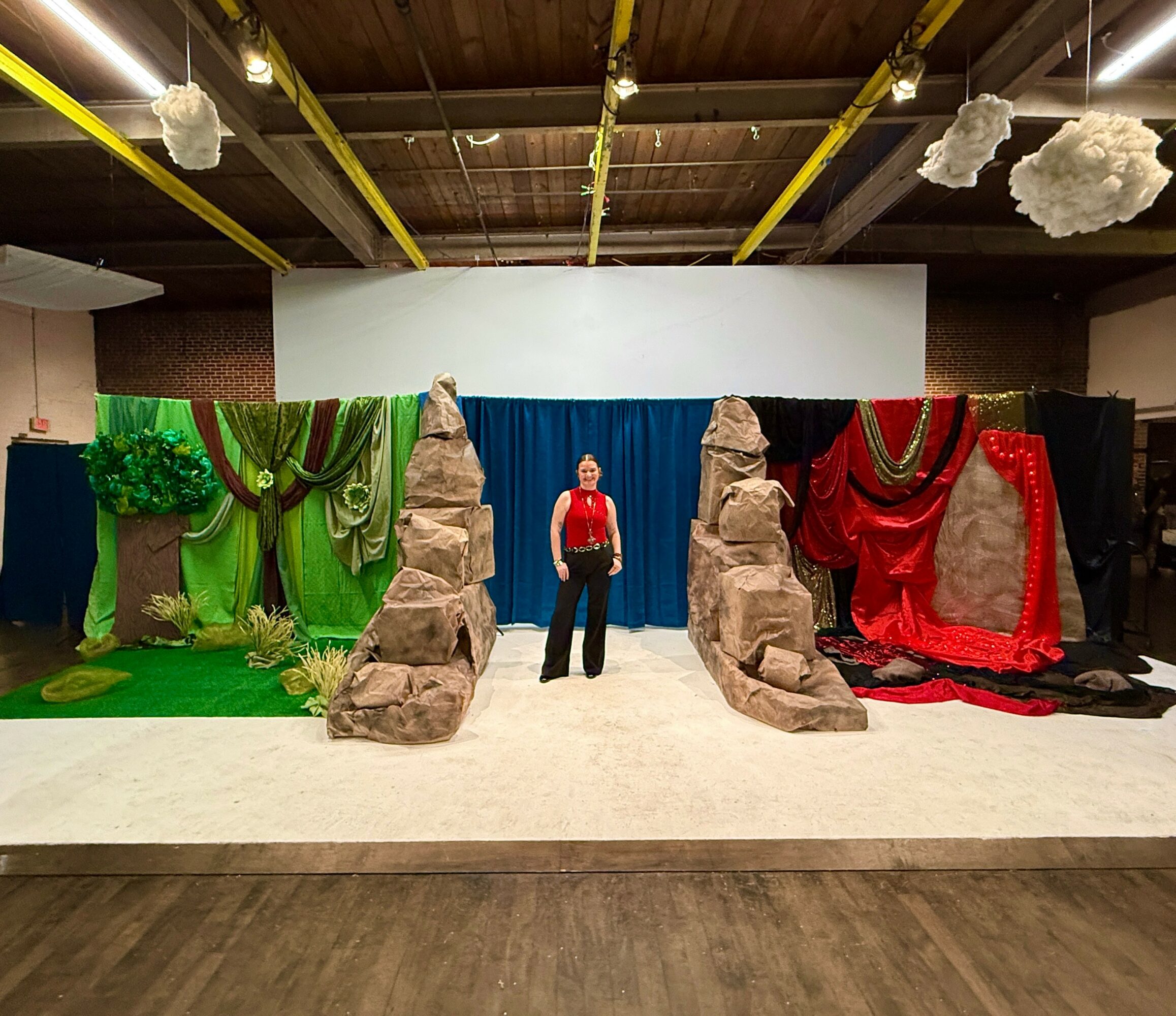 Stage with colorful drapes, large rocks, and a person standing in the center, set for a performance or event.