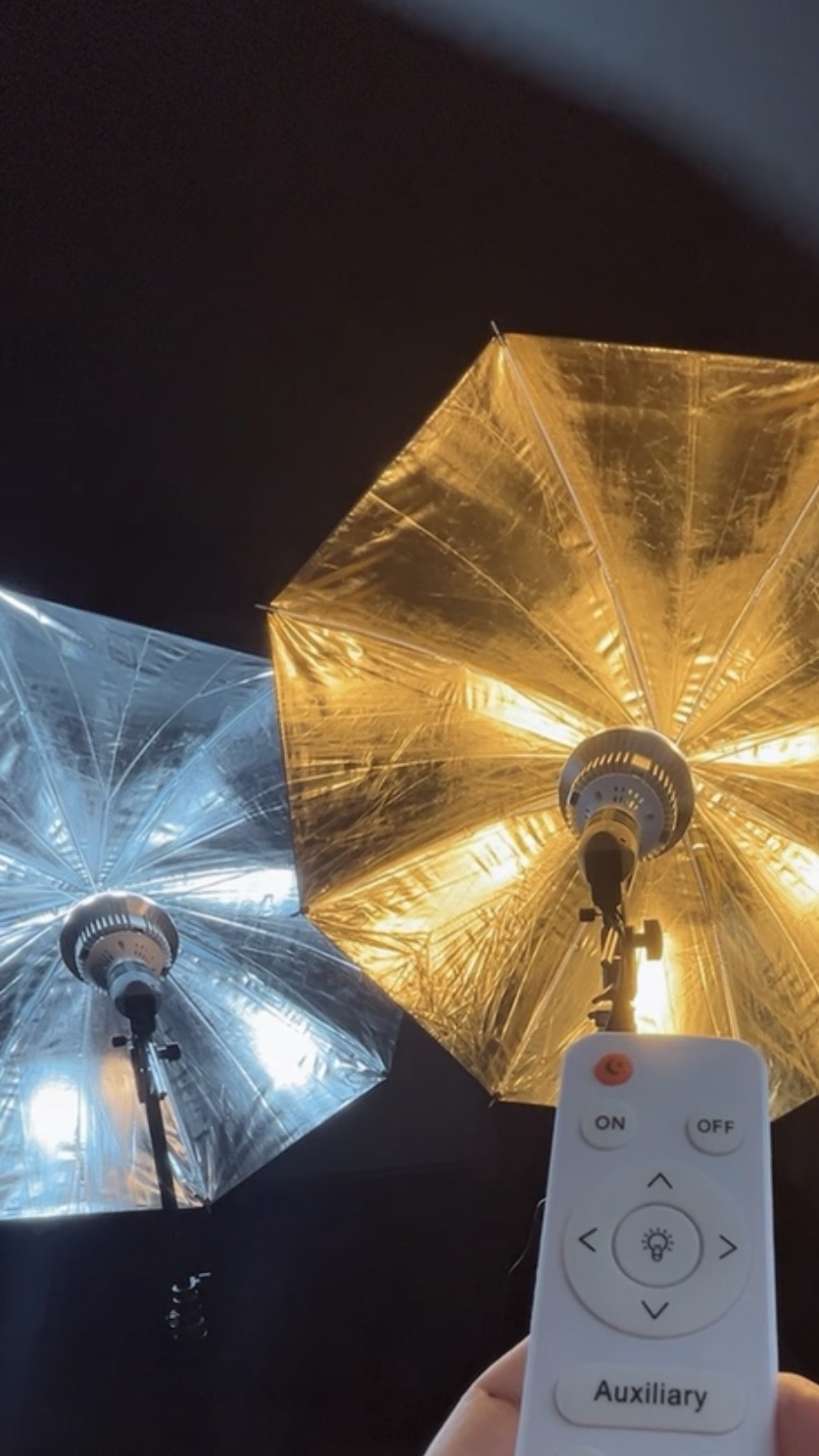 Two umbrellas, one blue and one gold, illuminated from below, with a remote control in the foreground.