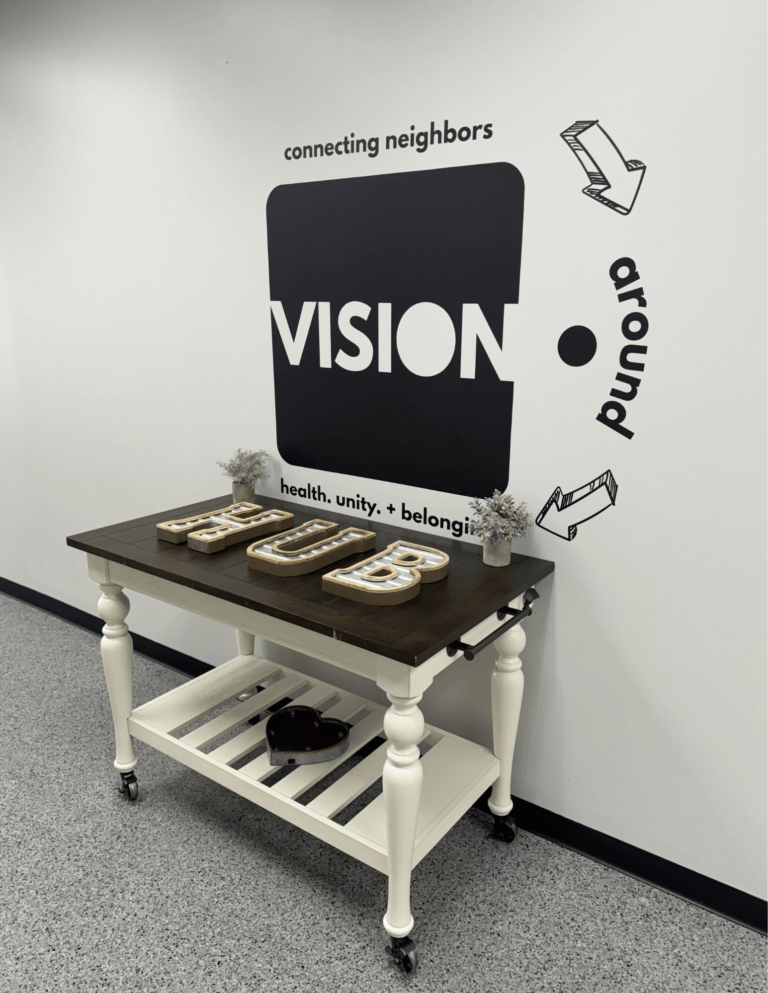 Wall with text and graphics, black rectangle with 'VISION' in white, arrows, and words like 'connecting neighbors' and 'around'.