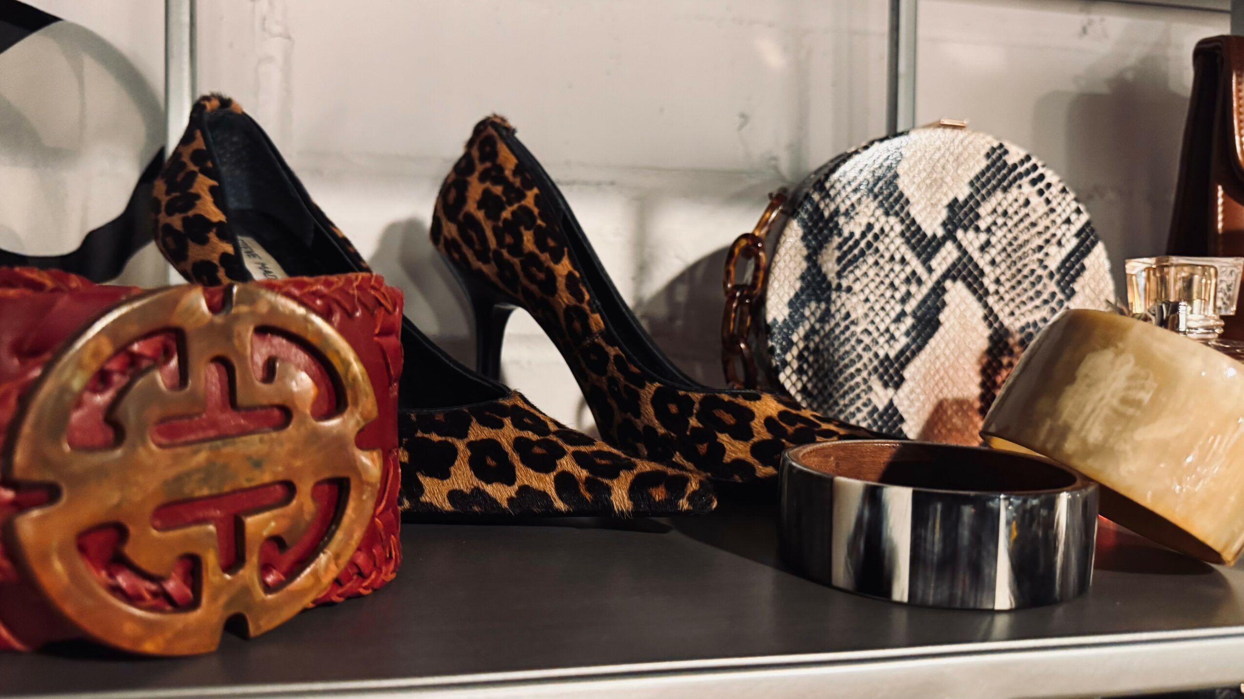Display of shoes, handbags, and accessories including leopard print shoes, a snake print bag, and jewelry.