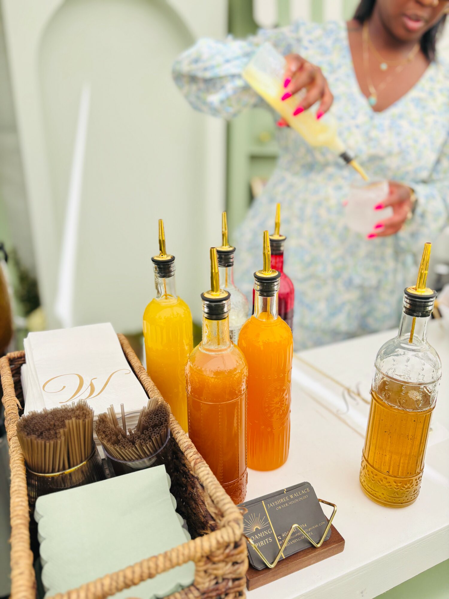 Person pouring yellow sauce into bottles on a table with condiments and napkins.