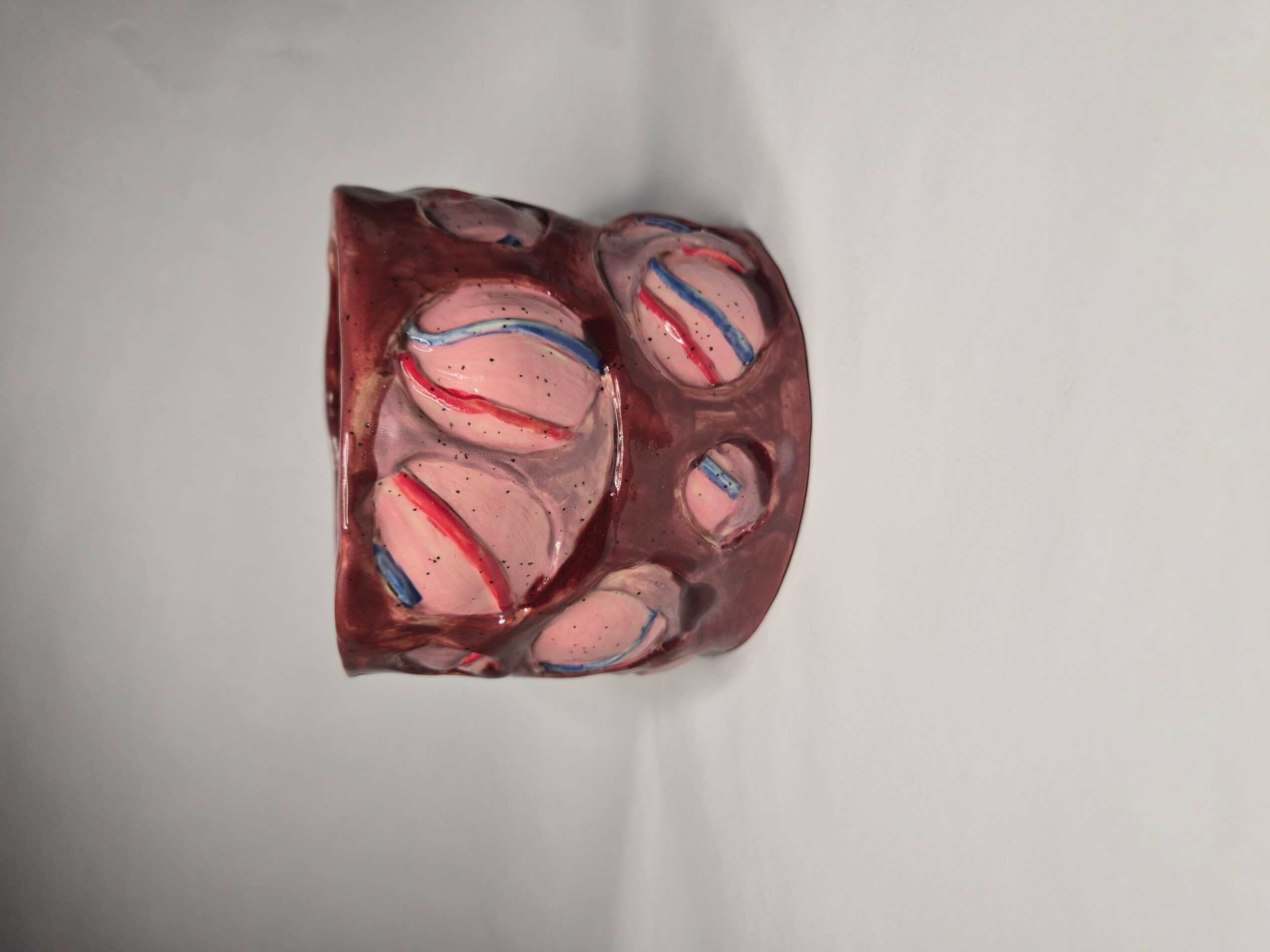 A box of assorted candies with pink, white, and red striped patterns, placed on a white surface.