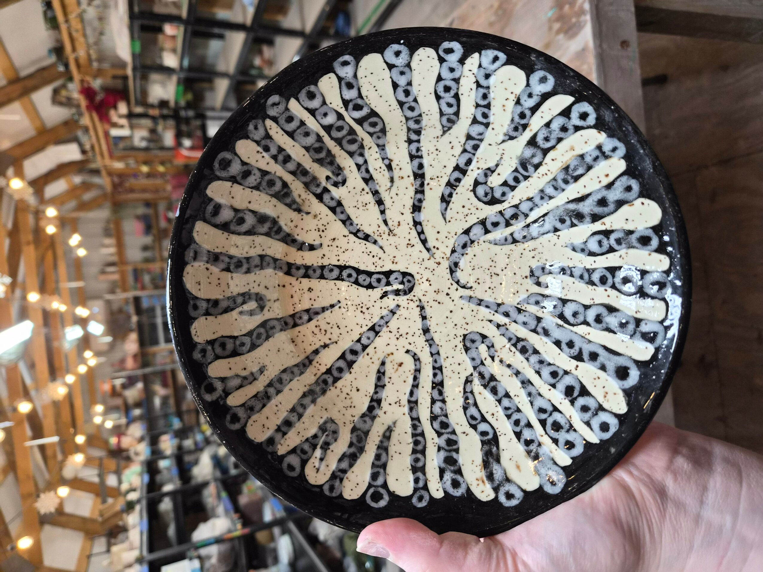 Circular object with a pattern of white and black lines radiating from the center, held by a person's hand.