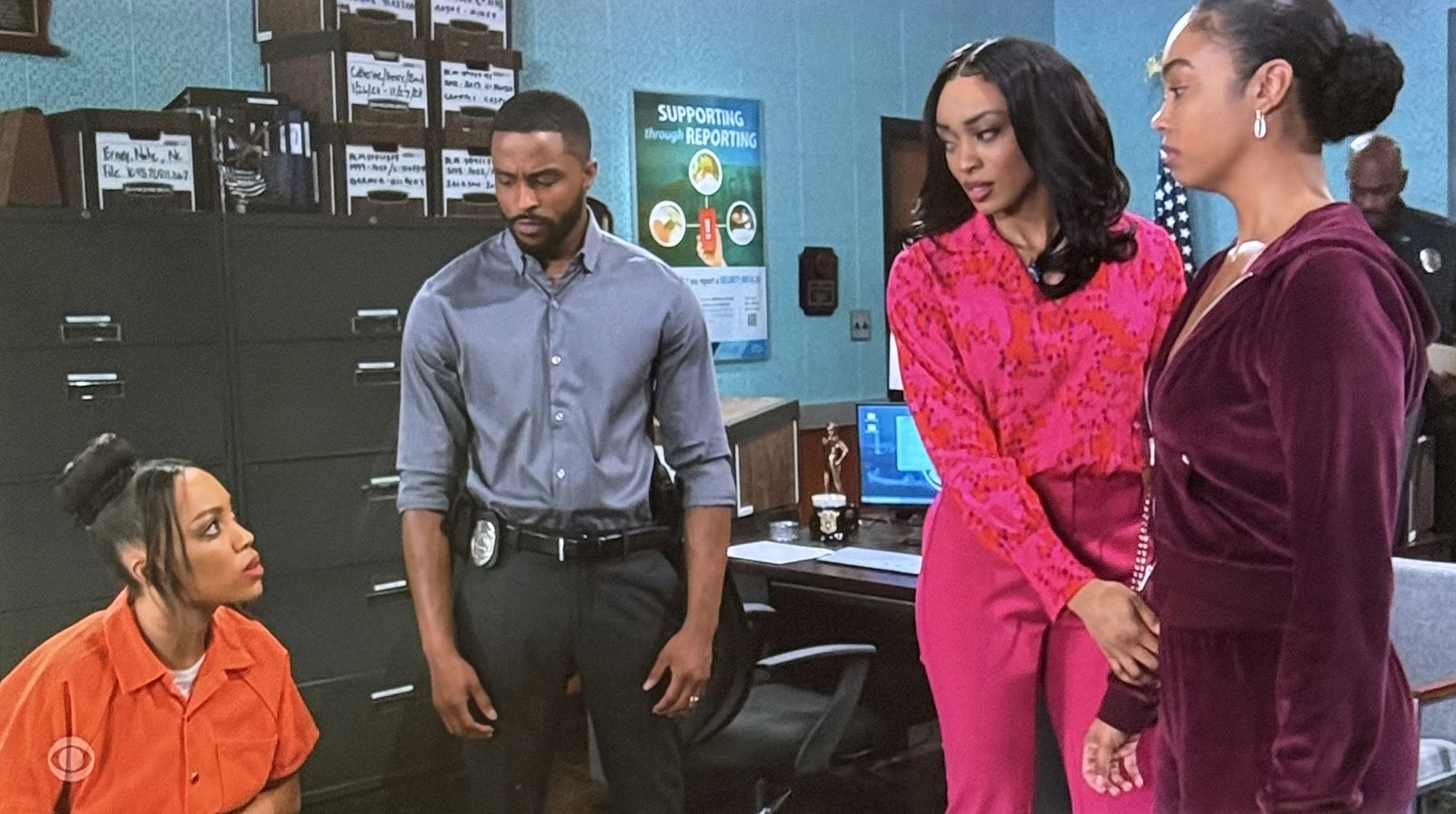 Four people in an office, two women standing and two people sitting, with office equipment in the background.
