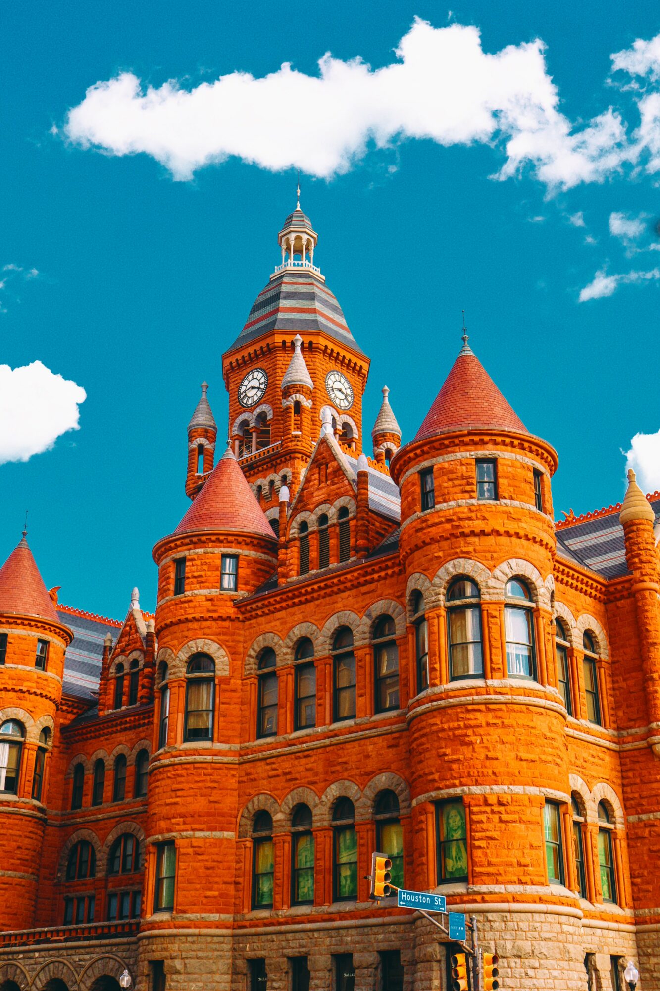 Red brick castle with turrets and arched windows under a blue sky with clouds