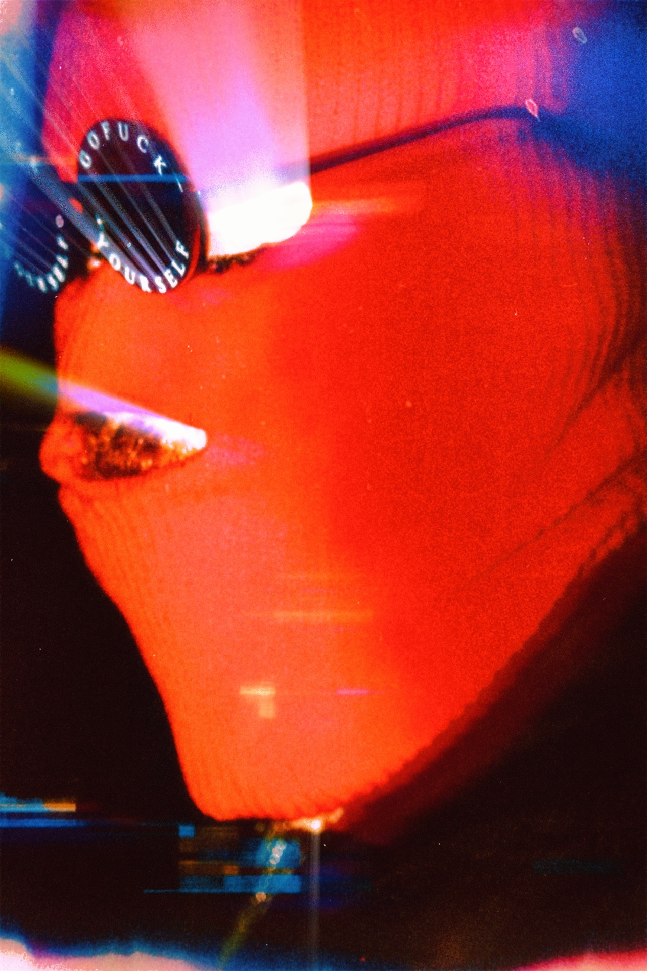 Close-up of a red object with a gauge and a light, with bright reflections and a dark background.