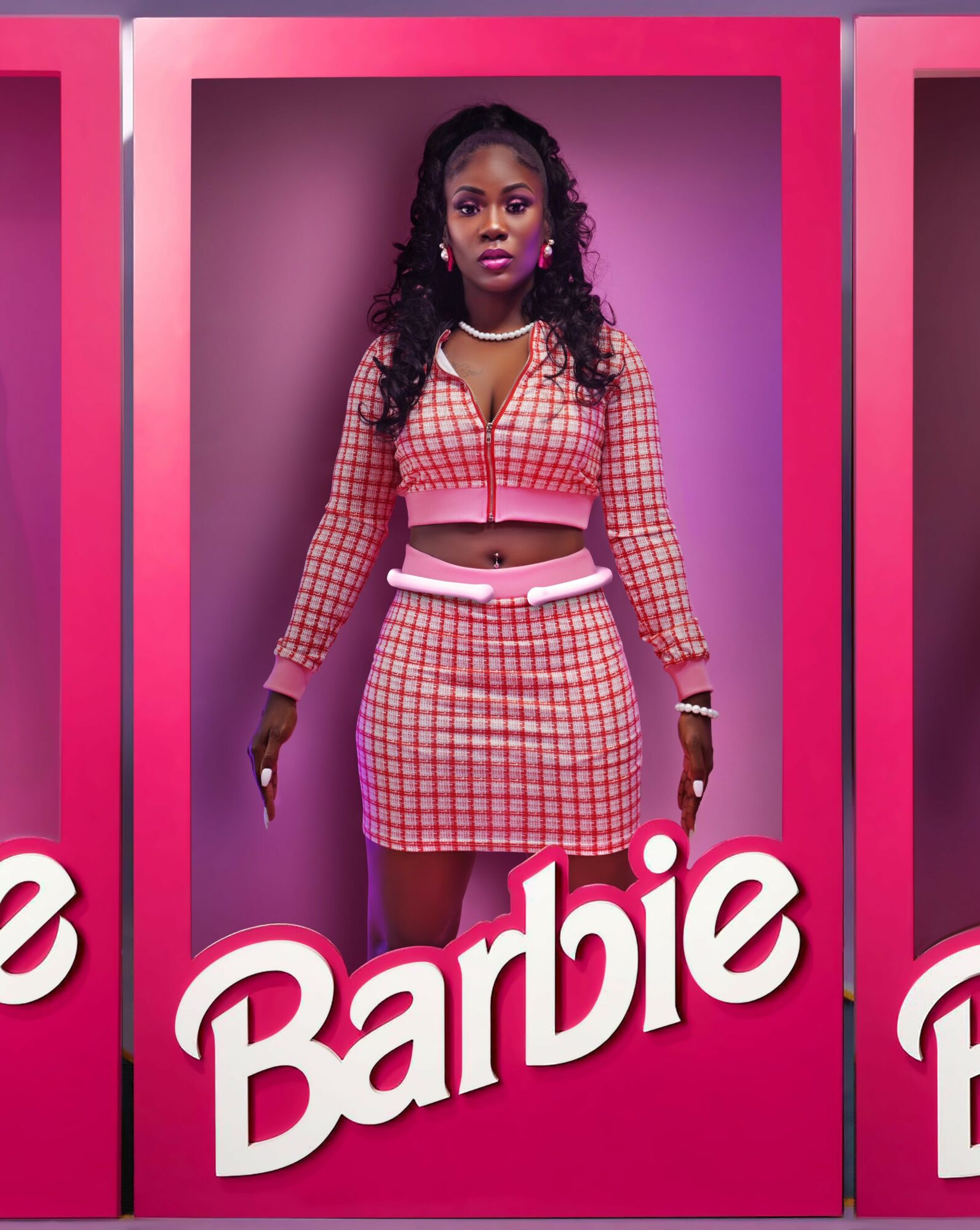 Young woman with dark curly hair in a pink checkered outfit, standing inside a pink frame with a purple background.