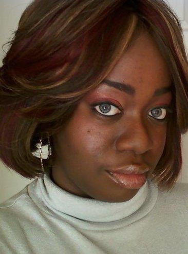 Close-up of a woman with shoulder-length hair, wearing a white turtleneck, looking at the camera.