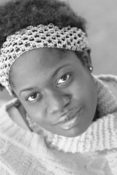 Close-up of a young woman with a headband, looking at the camera, wearing a sweater.