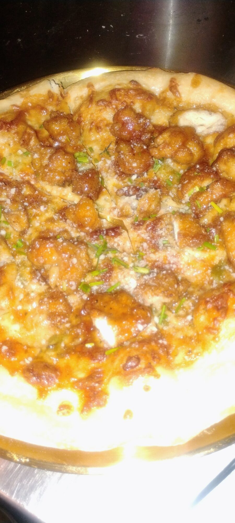 Close-up of a pizza with toppings including meat and vegetables, cheese, and sauce, on a white plate.