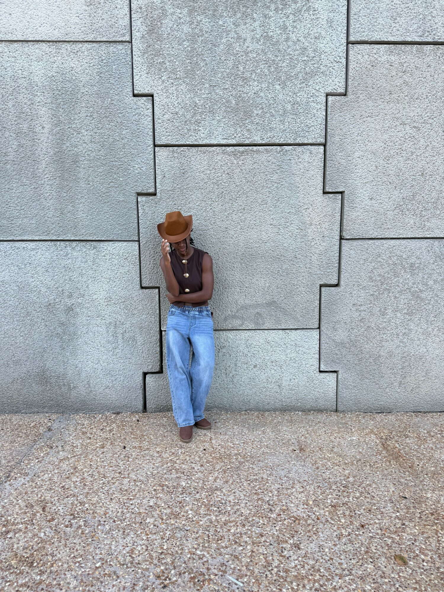 A small figurine of a person wearing a brown hat, dark shirt, and blue pants, standing on a tiled surface.