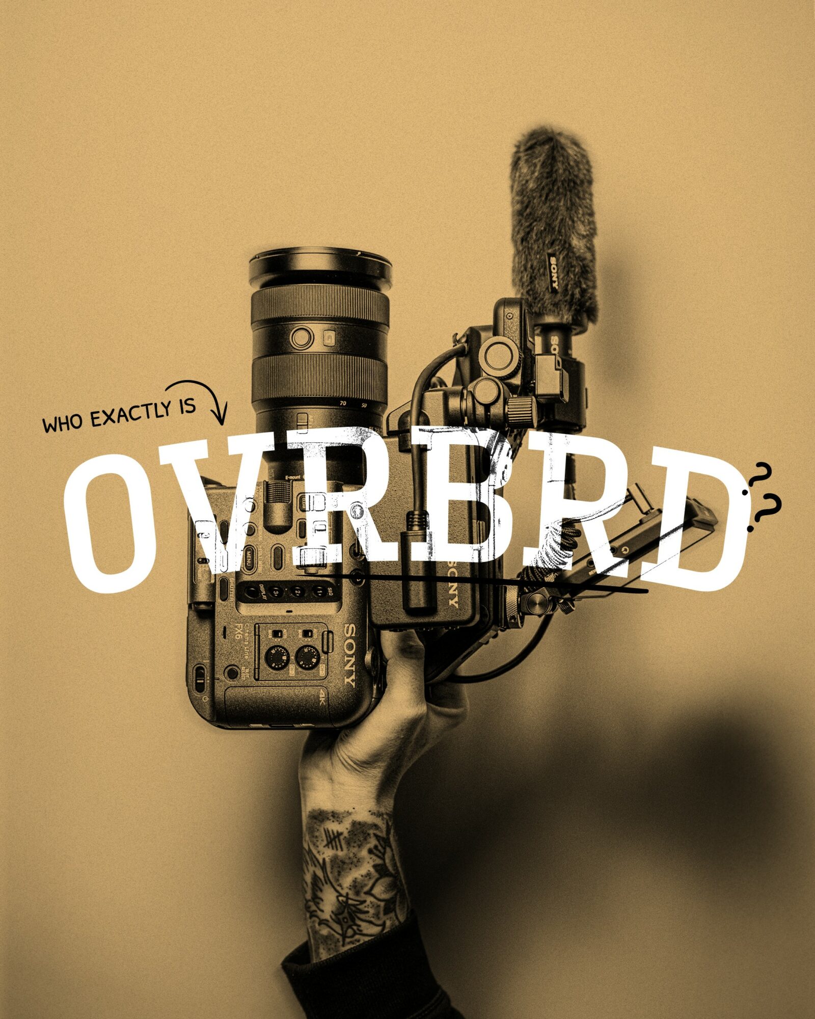 A hand with a tattoo holds a camera with a microphone attached, against a beige background.
