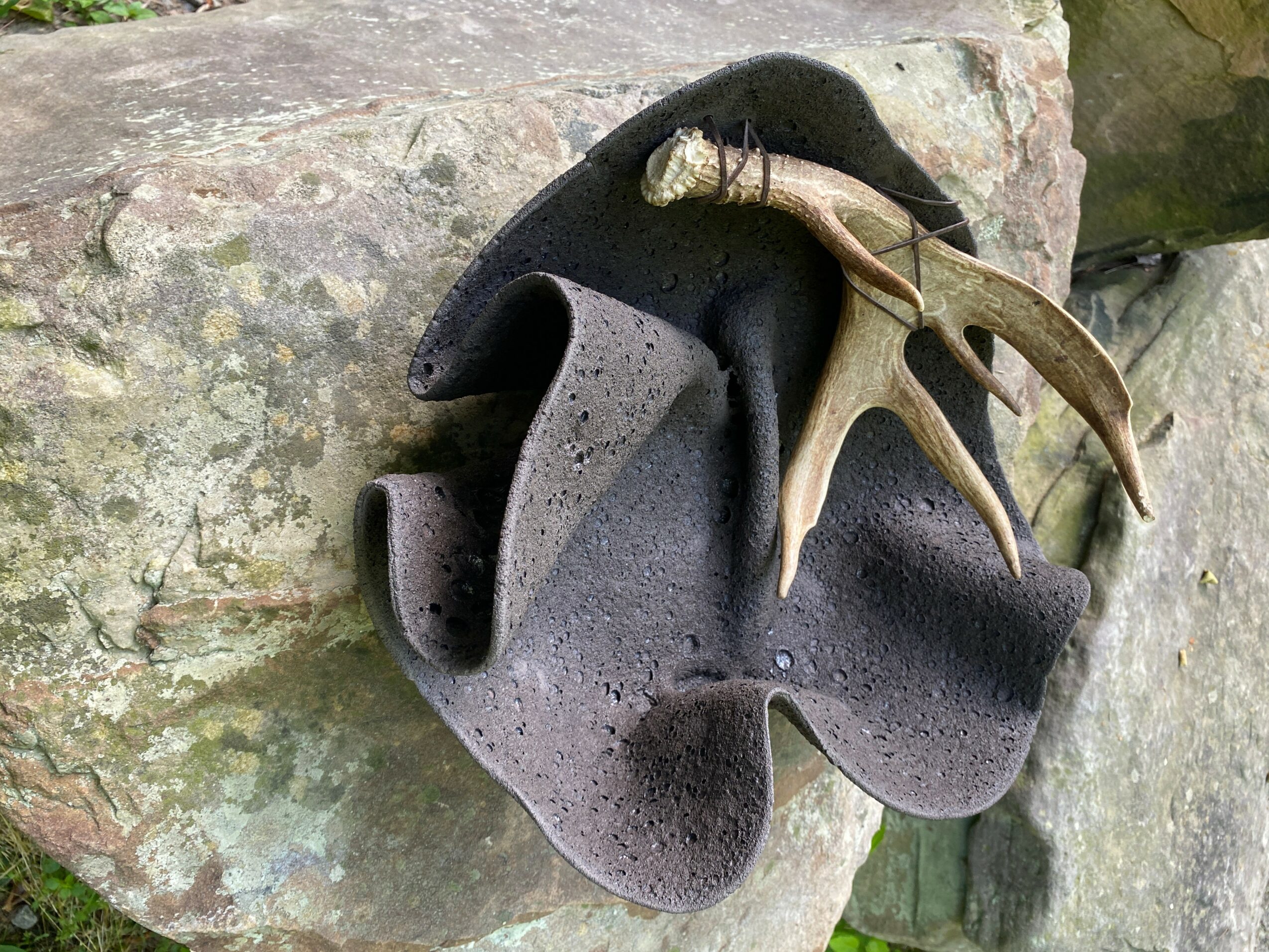 A sculpture of a bear's head with antlers mounted on a rock surface.