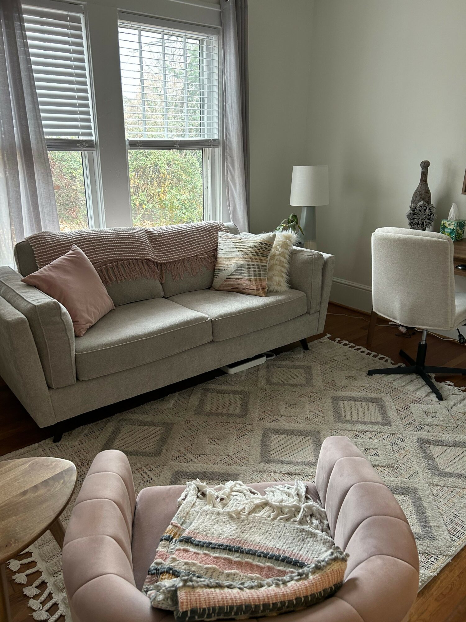 Living room with a sofa, armchair, window, and decorative items, viewed sideways.